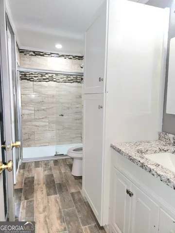 a bathroom with a granite countertop shower sink and toilet