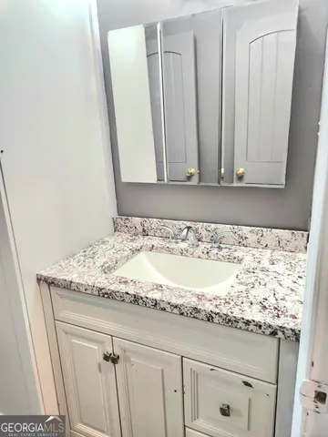 a bathroom with a granite countertop sink and a mirror