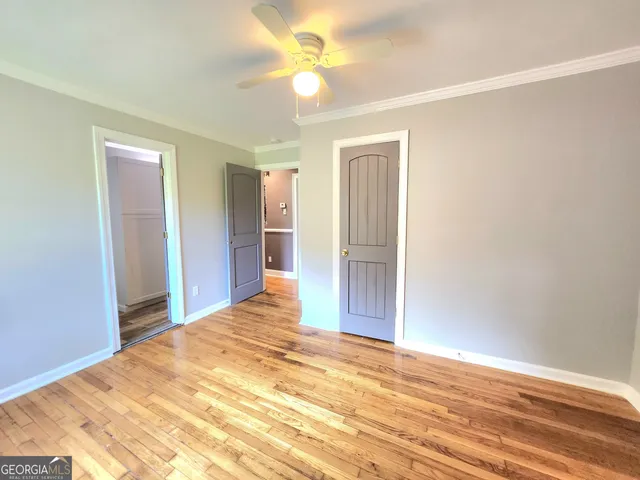 a view of a bedroom with wooden floor and a ceiling fan