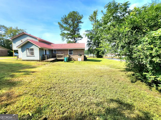 a view of a house with a big yard and large trees