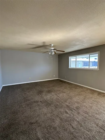 an empty room with a chandelier fan and windows