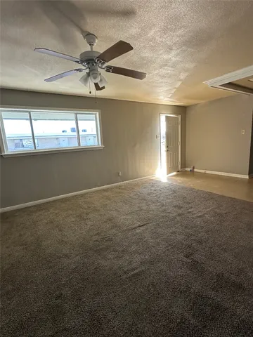 an empty room with a chandelier fan and windows
