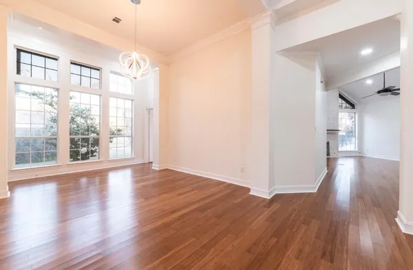 a view of empty room with wooden floor and fan