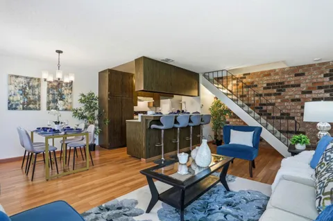 a living room with furniture a rug and a dining table with wooden floor