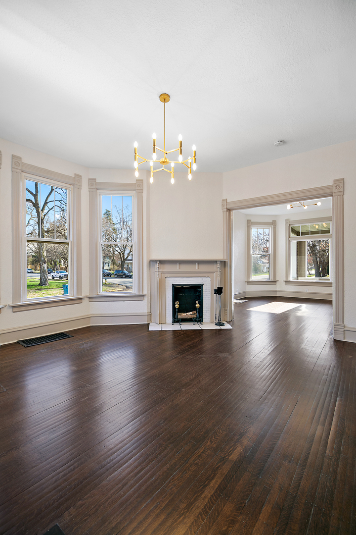 505 South Indiana Avenue Kankakee, IL 60901 - Photo 7 of 32 an empty room with wooden floor fireplace and windows