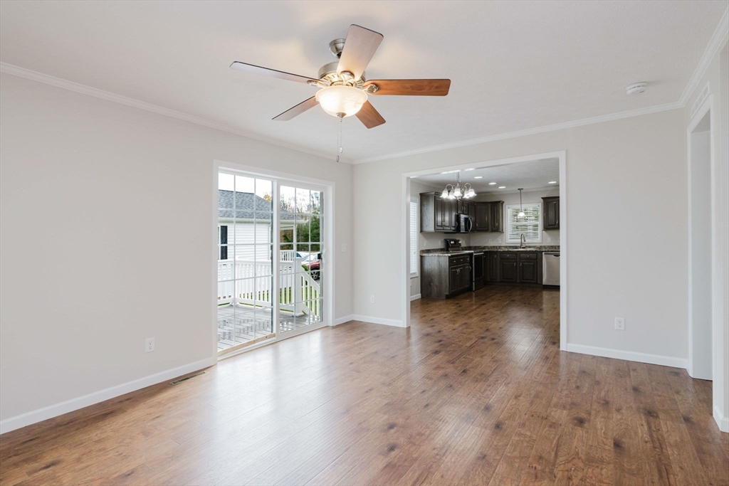 17 Maries Way Raynham, MA 02767 - Photo 15 of 39 an empty room with wooden floor fan and kitchen view