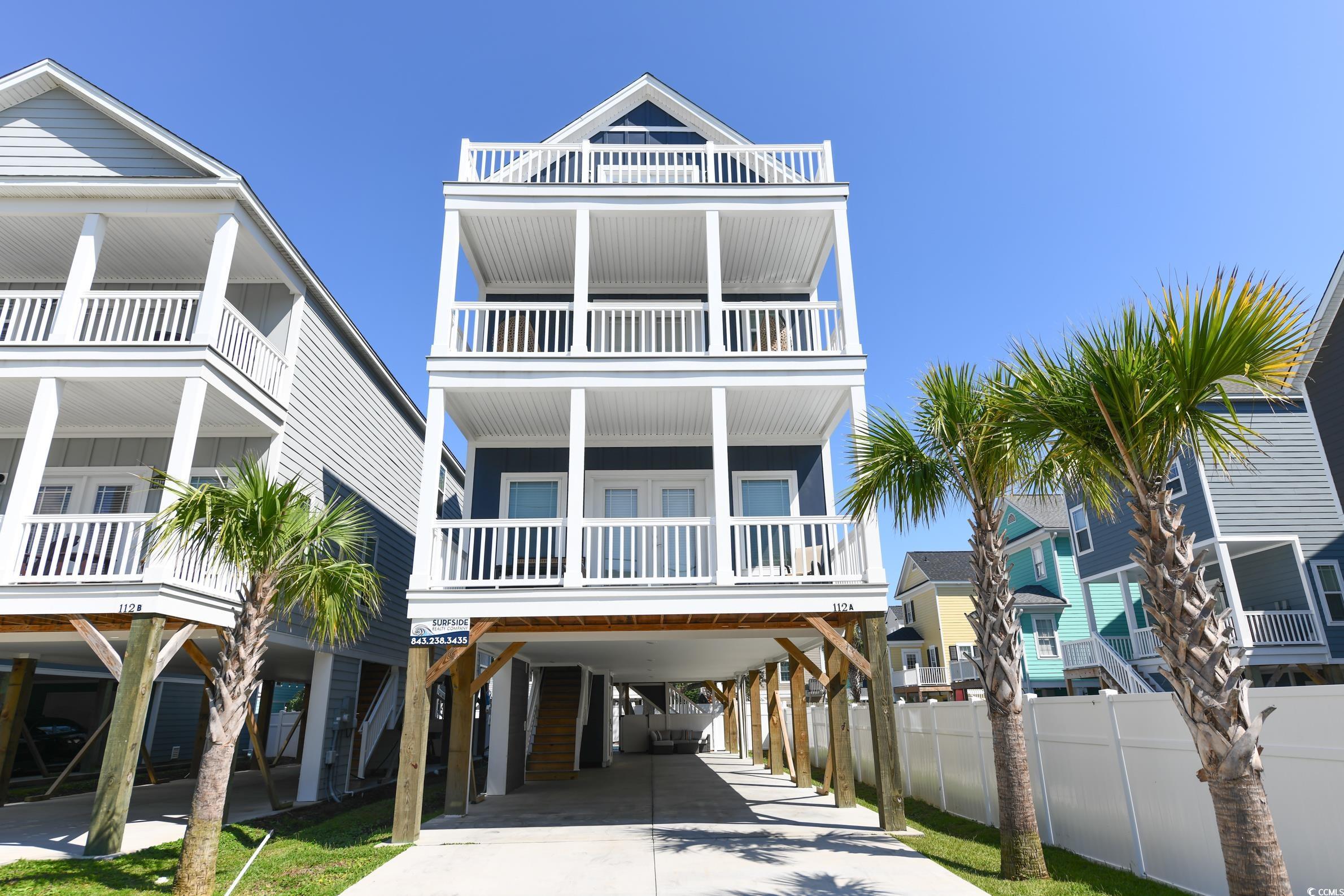 Coastal home featuring a carport, a balcony, and driveway