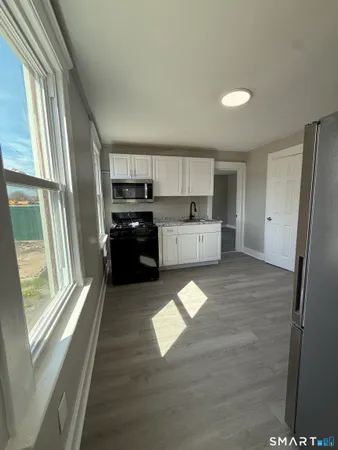 a kitchen with stainless steel appliances granite countertop a refrigerator a sink dishwasher a stove and white countertops with wooden floor