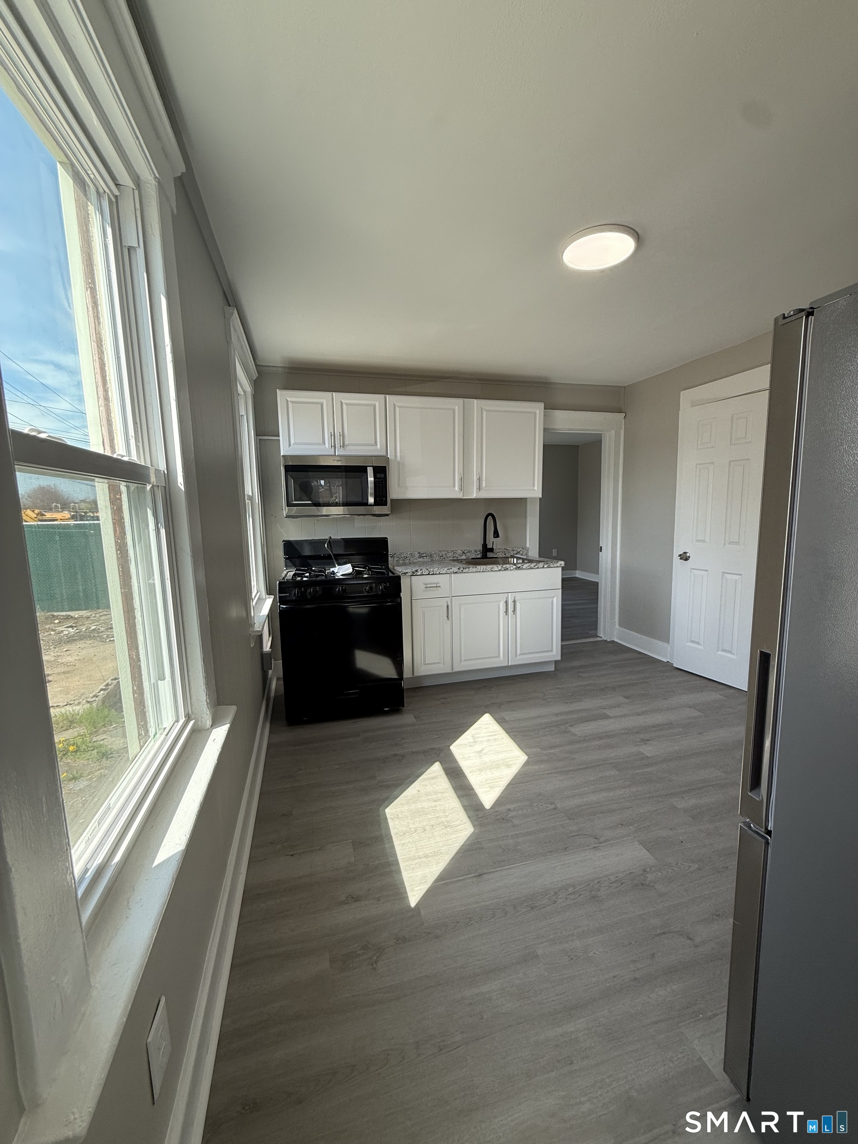 420 Short Beach Road East Haven, CT 06512 - Photo 4 of 23 a kitchen with stainless steel appliances granite countertop a refrigerator a sink dishwasher a stove and white countertops with wooden floor