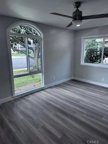 an empty room with wooden floor fan and windows