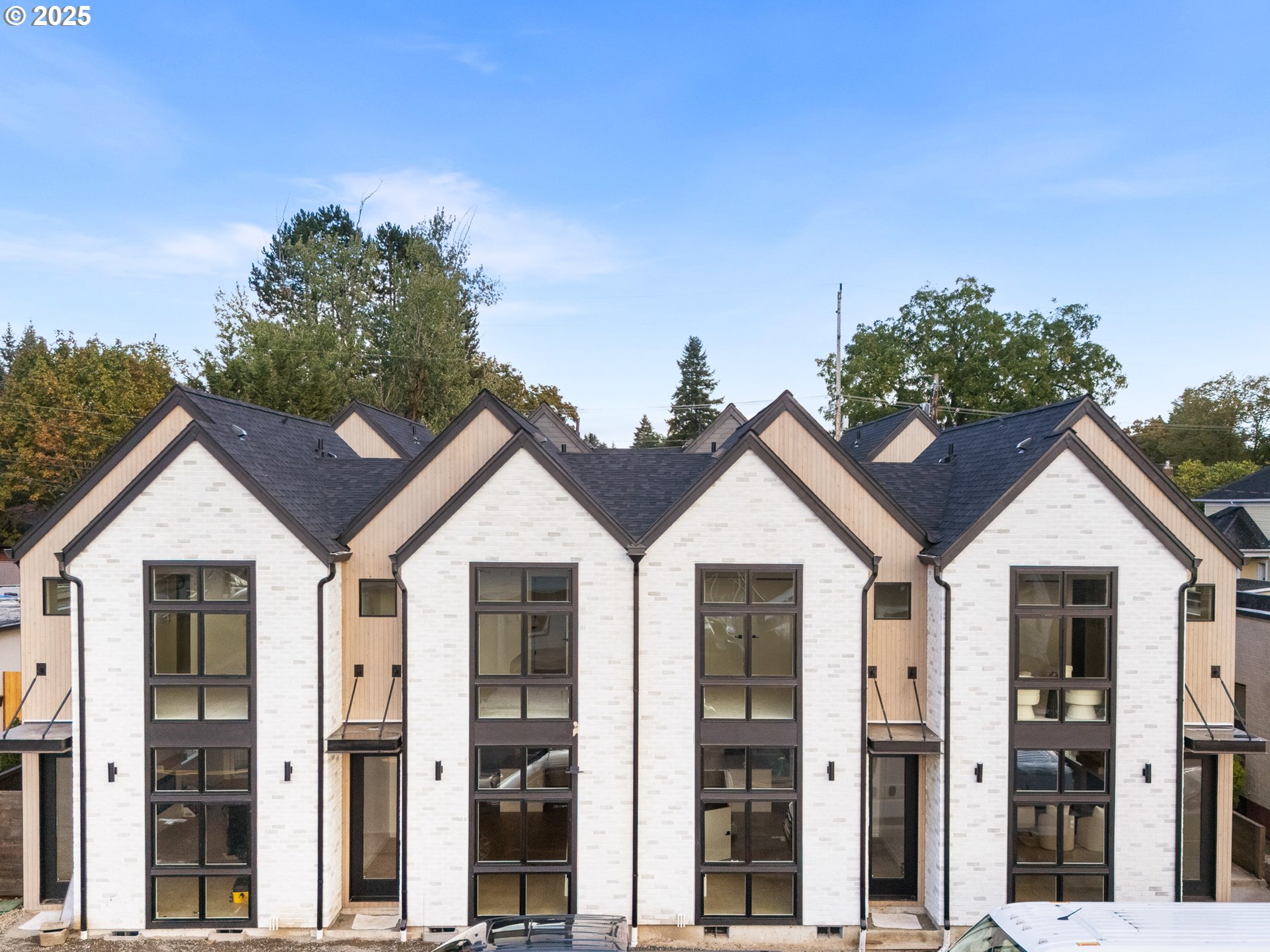 a view of a white house with a small yard and large trees