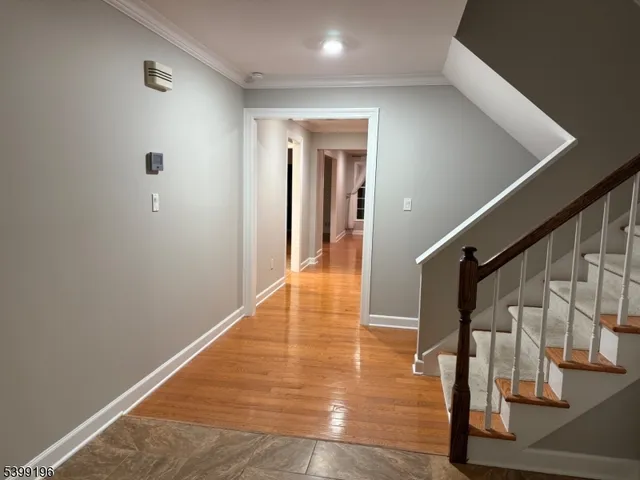 a view of an empty room with chandelier and wooden floor
