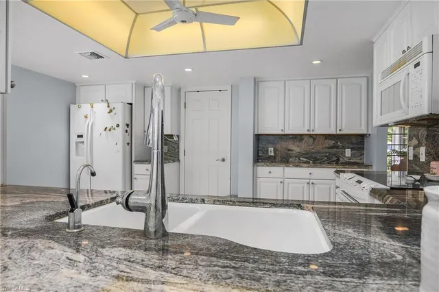 a kitchen with stainless steel appliances granite countertop a refrigerator a stove and white cabinets with wooden floor