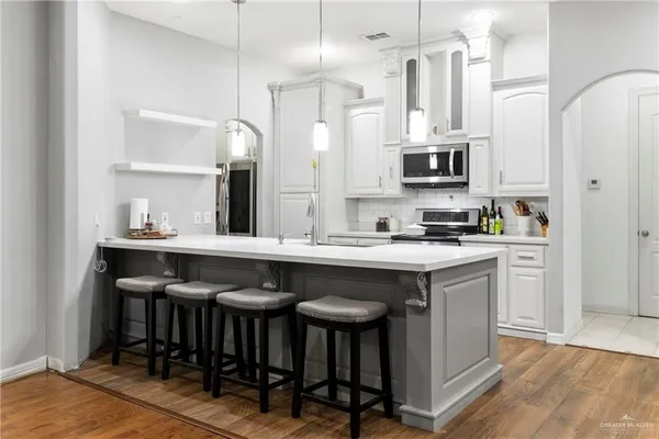 a kitchen with stainless steel appliances granite countertop a table chairs sink and cabinets