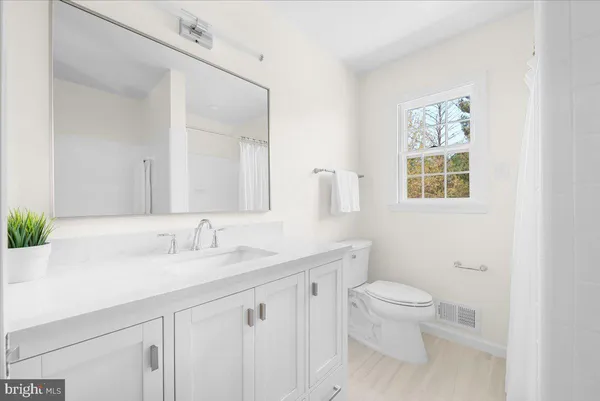 a bathroom with a toilet a sink a mirror and a shower