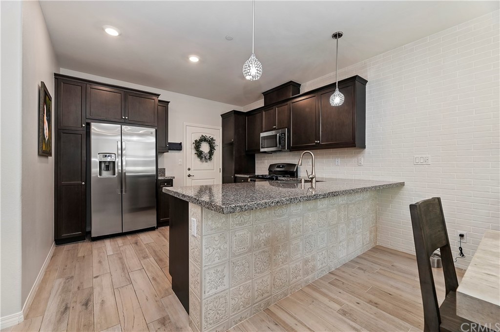 14557 Sienna Place Eastvale, CA 92880 - Photo 13 of 35 a kitchen with stainless steel appliances granite countertop a sink refrigerator and microwave