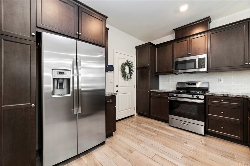 14557 Sienna Place Eastvale, CA 92880 - Photo 14 of 35 a kitchen with stainless steel appliances and wooden cabinets
