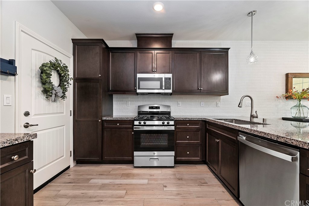 14557 Sienna Place Eastvale, CA 92880 - Photo 15 of 35 a kitchen with stainless steel appliances granite countertop a stove a sink and a refrigerator