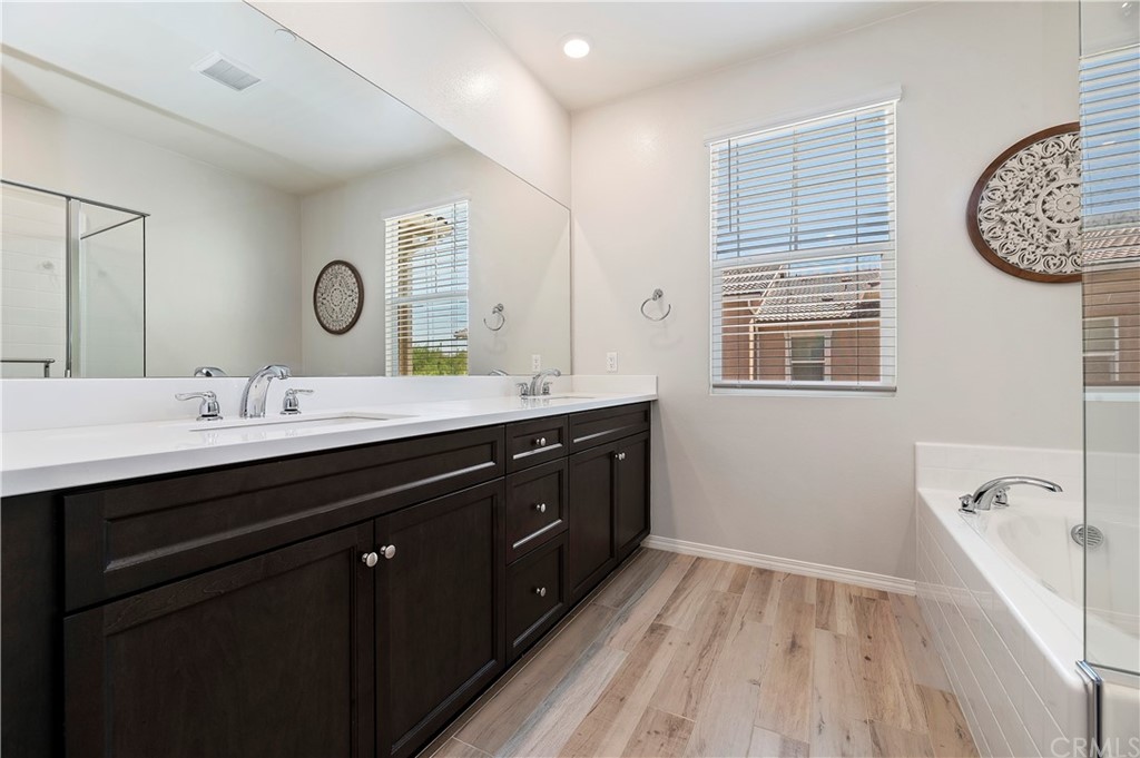 14557 Sienna Place Eastvale, CA 92880 - Photo 26 of 35 a bathroom with a double vanity sink a mirror and a bathtub