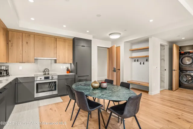 a kitchen with stainless steel appliances granite countertop a kitchen island a stove a dining table and chairs with wooden floor