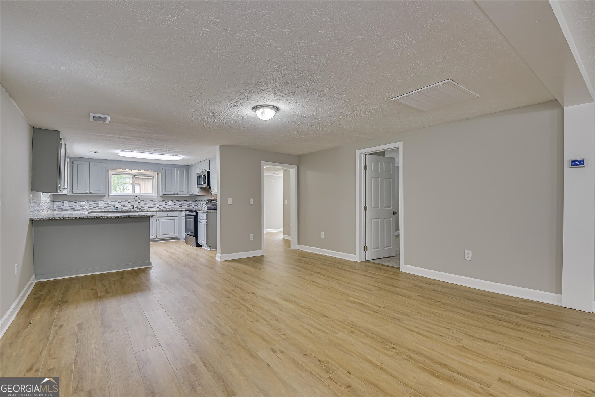 1321 Brett Road Wadley, GA 30477 - Photo 13 of 47 a view of an empty room and kitchen with wooden floor