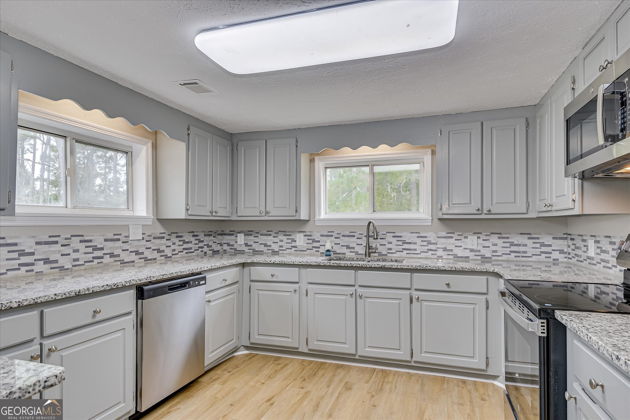 1321 Brett Road Wadley, GA 30477 - Photo 21 of 47 a kitchen with granite countertop white cabinets sink and window