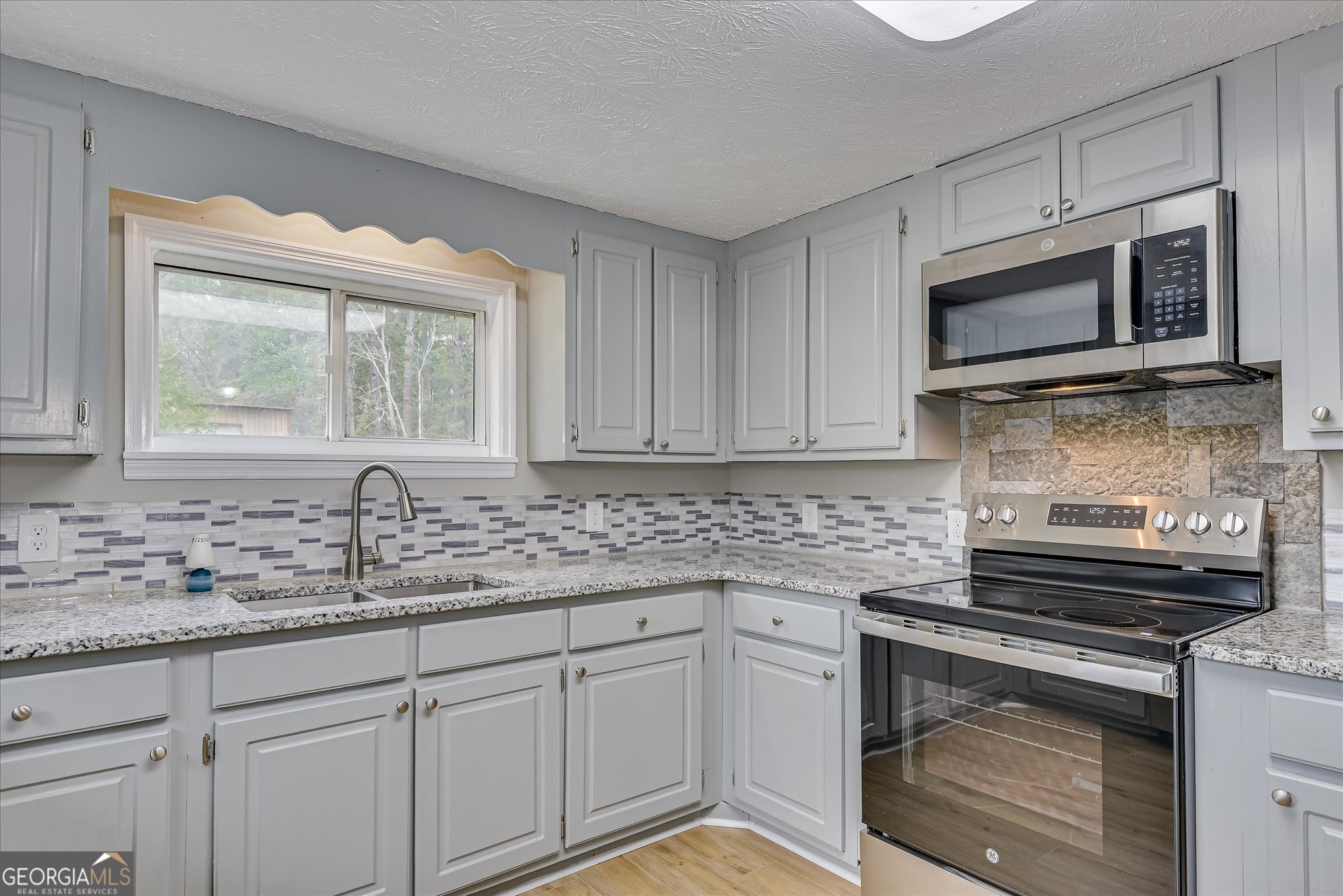 1321 Brett Road Wadley, GA 30477 - Photo 22 of 47 a kitchen with stainless steel appliances white cabinets granite counter tops and a window