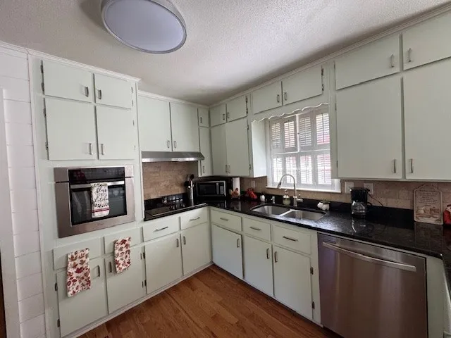 a kitchen with stainless steel appliances granite countertop a sink cabinets and wooden floor