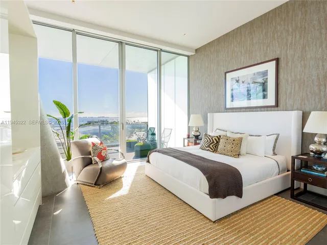 a bedroom with a bed and large windows