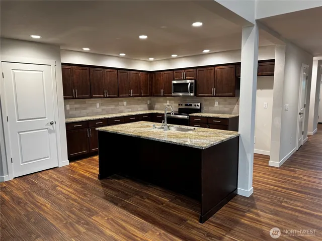 a kitchen with kitchen island granite countertop a sink cabinets and stainless steel appliances
