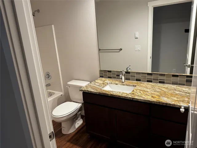 a bathroom with a granite countertop toilet sink and mirror