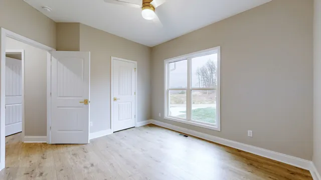 an empty room with wooden floor and windows