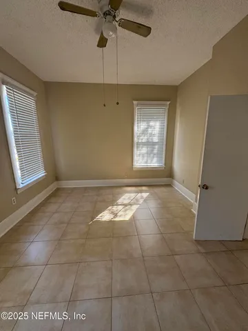 an empty room with windows and fan