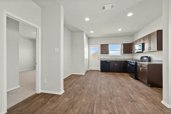 a large kitchen with wooden floors and stainless steel appliances