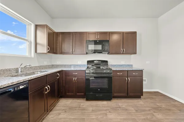 a kitchen with stainless steel appliances granite countertop a stove a sink and a microwave