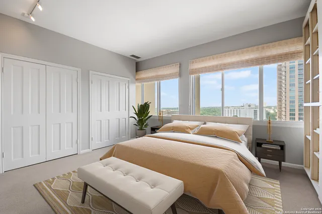 a bedroom with a bed and large windows