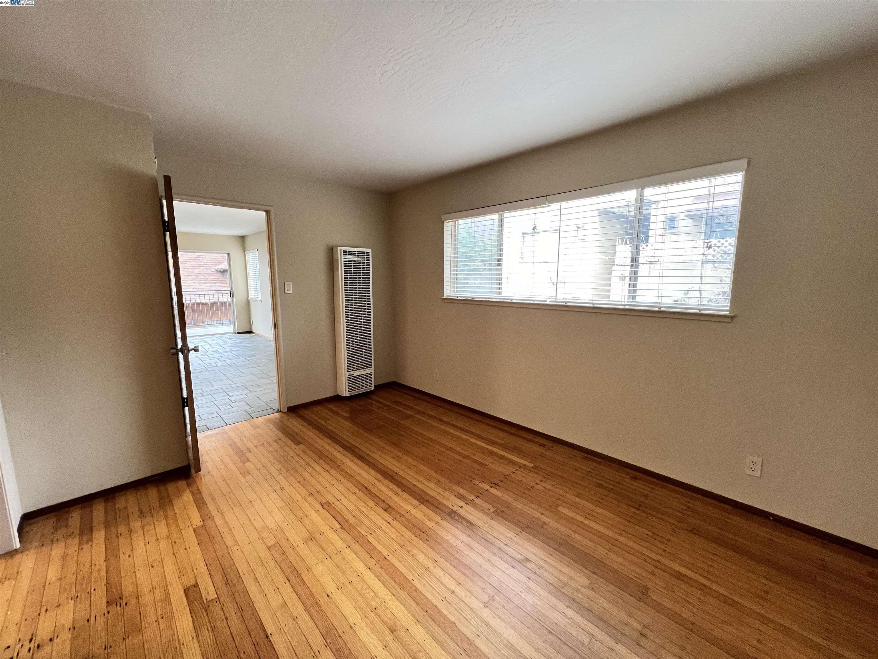 2418 Ashby Avenue, Unit B Berkeley, CA 94705 - Photo 10 of 14 a view of an empty room with wooden floor and a window