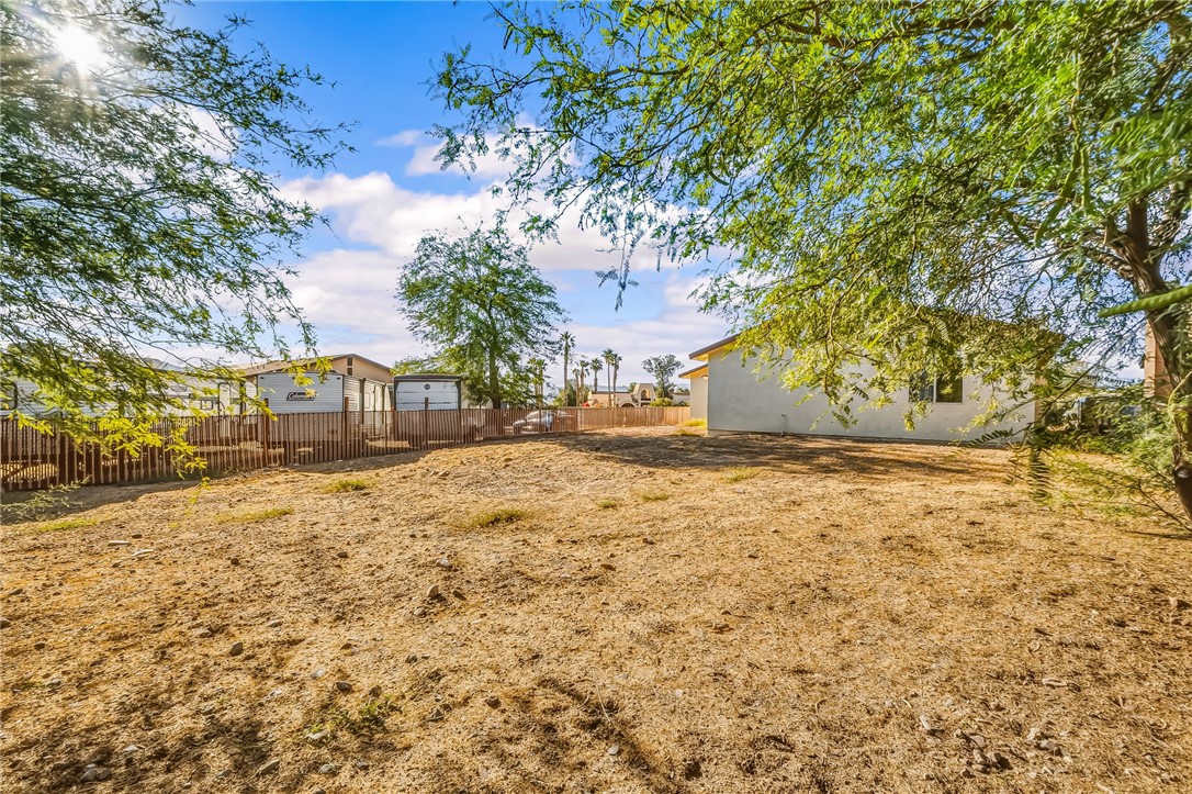 1720 Valencia Road Fort Mohave, AZ 86426 - Photo 5 of 32 Expansive backyard space featuring natural ground cover, mature trees, and a perimeter fence