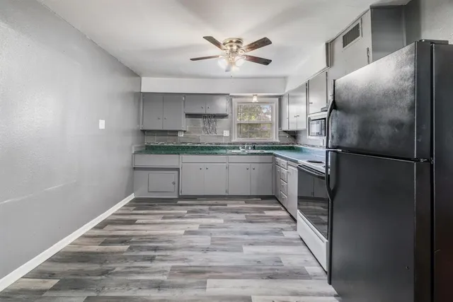 a kitchen with stainless steel appliances granite countertop a refrigerator a sink a stove a dining table and chairs