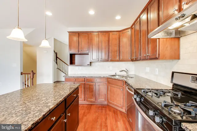 a kitchen with stainless steel appliances granite countertop a stove a sink and a microwave