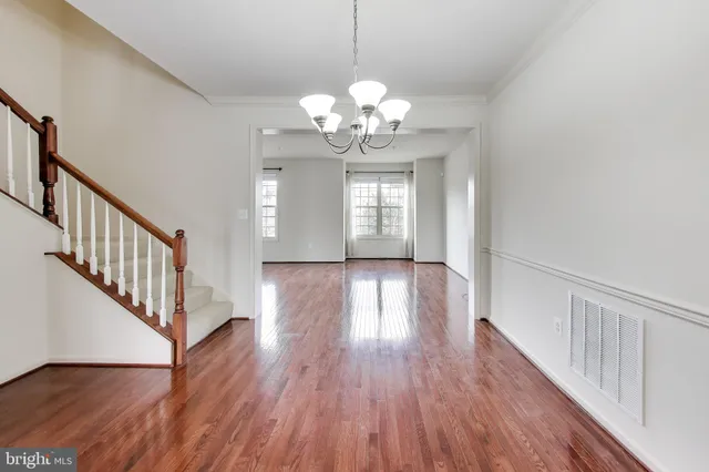 a view of a hallway with wooden floor and a chandelier