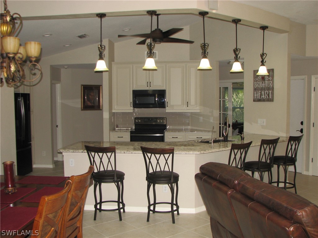 15252 Briar Ridge Circle Fort Myers, FL 33912 - Photo 6 of 25 a kitchen with stainless steel appliances kitchen island granite countertop a dining table chairs and a refrigerator