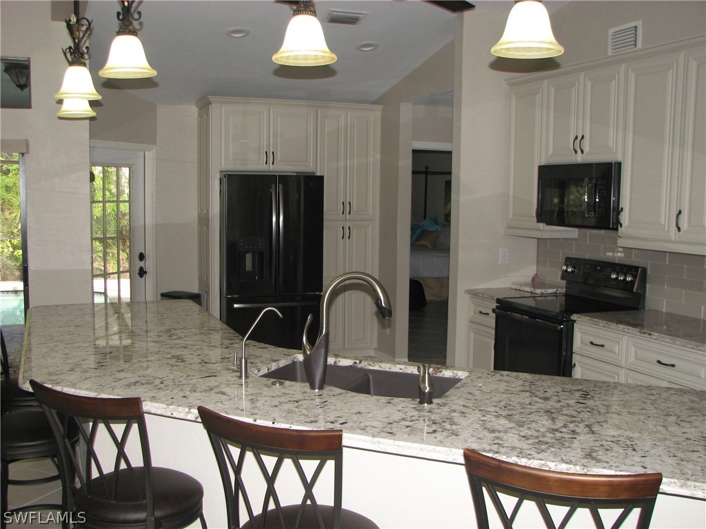15252 Briar Ridge Circle Fort Myers, FL 33912 - Photo 7 of 25 a kitchen with granite countertop a table chairs stove and cabinets