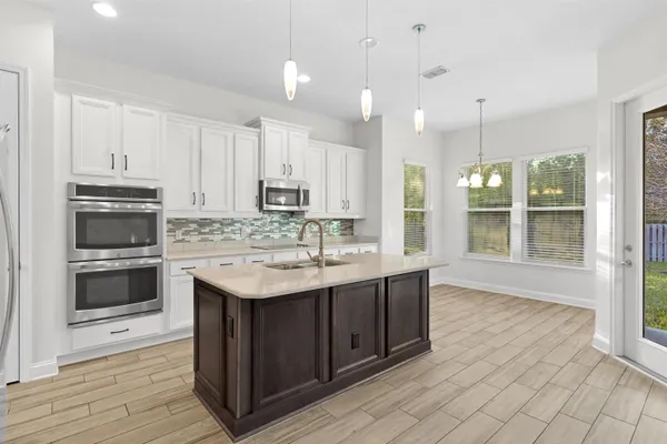 a kitchen with kitchen island a sink a stove and cabinets