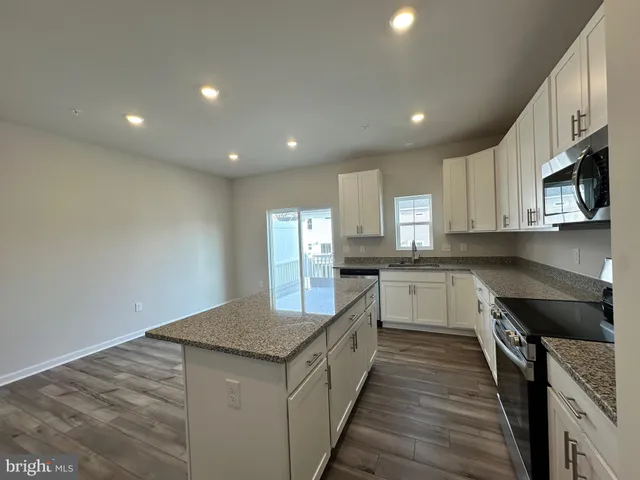 a kitchen with granite countertop white cabinets and stainless steel appliances