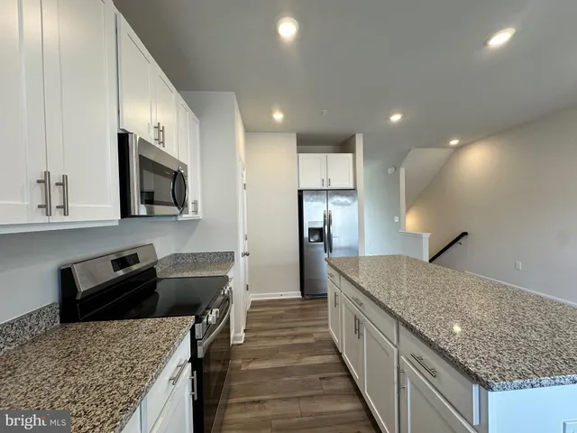 a kitchen with stainless steel appliances granite countertop a sink a stove and a refrigerator