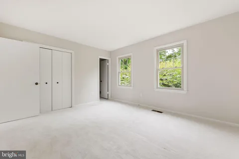 a view of an empty room with window and chandelier fan