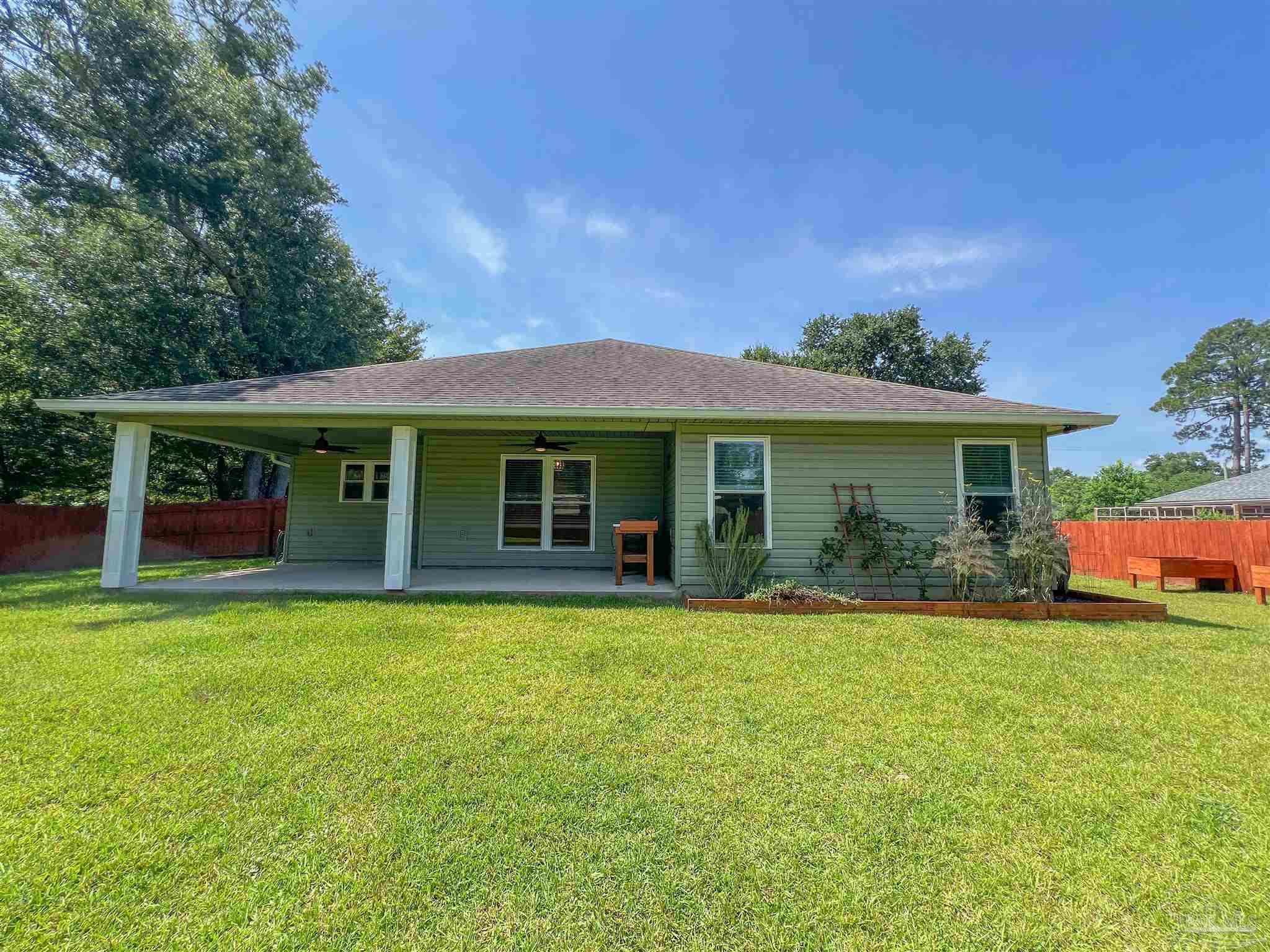 4906 Landmark Lane Pace, FL 32571 - Photo 32 of 34 a front view of a house with a garden and porch