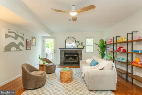 a living room with furniture a fireplace and a ceiling fan