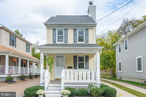 a view of a brick house with a yard plants and large tree